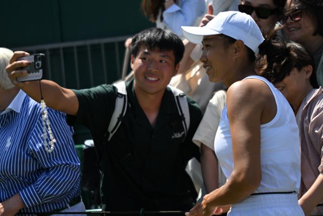 (250704) -- LONDON, July 4, 2025 (Xinhua) -- Zhang Shuai (R) takes a selfie with audience after the women's doubles second round match between Zhang Shuai (China)/Ekaterina Alexandrova (Russia) and Hozumi Eri (Japan)/Aldila Sutjiadi (Indonesia) at the Wimbledon Tennis Championships in London, Britain, July 4, 2025. (Xinhua/Li Ying)