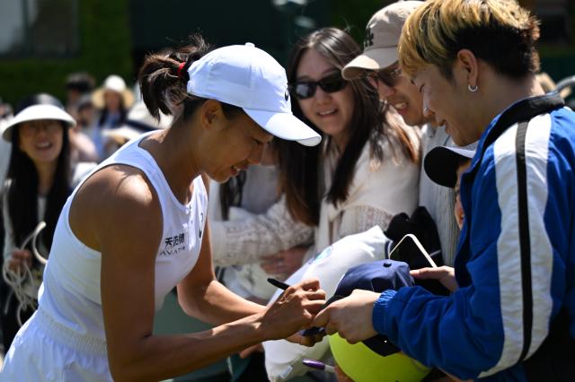 (250704) -- LONDON, July 4, 2025 (Xinhua) -- Zhang Shuai (L) signs autographs for fans after the women's doubles second round match between Zhang Shuai (China)/Ekaterina Alexandrova (Russia) and Hozumi Eri (Japan)/Aldila Sutjiadi (Indonesia) at the Wimbledon Tennis Championships in London, Britain, July 4, 2025. (Xinhua/Li Ying)