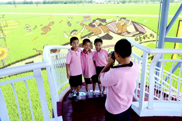 (250705) -- HEGANG, July 5, 2025 (Xinhua) -- Students pose for a photo at a rice science and technology demonstration park under the Beidahuang Group in Hegang City in northeast China's Heilongjiang Province on July 4, 2025. At present, in the rice producing areas of Heilongjiang Province, various magnificent rice field pictures "drawn" by different varieties of rice are unfolding on the vast black soil. (Photo by Li Ang/Xinhua)