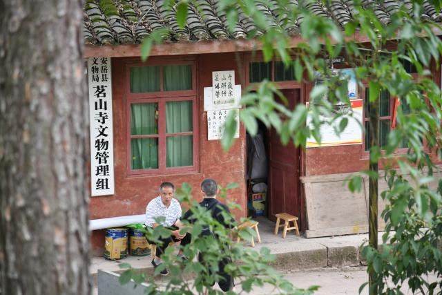 (250705) -- ZIYANG, July 5, 2025 (Xinhua) -- Zeng Xiangyu talks with a tourist outside his office next to Mingshan Temple in Shiyang Town of Ziyang City, southwest China's Sichuan Province, June 14, 2025. On top of Hutou Mountain in Shiyang Town of Ziyang City, a 76-year-old man named Zeng Xiangyu is a familiar sight to locals. Accompanied by his dog, he patrols the circular path around Mingshan Temple, meticulously inspecting each stone carving.
   Dating back to the Tang Dynasty (618-907), Mingshan Temple houses over 60 statues inside 13 caves. Most of these magnificent works of artistry were chiseled during the Song Dynasty (960-1127).
   In the 1980s, Zeng first came to the mountain with his uncle for temple renovation work. Since then, he has devoted his life to safeguarding these relics. When Mingshan Temple was listed as a national key cultural relics protection site in 2006, Zeng formally became its on-site cultural heritage administrator.
   Today, as visitors flock to Mingshan Temple, Zeng occasionally steps into a part-time role as a guide, narrating centuries-old tales. He has expressed that he wishes to protect these sculptural treasures passed down from ancestors to future generations. (Xinhua/Xu Bingjie)
