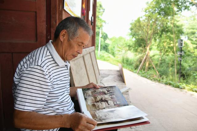 (250705) -- ZIYANG, July 5, 2025 (Xinhua) -- Zeng Xiangyu reads a photo album about stone carvings at Mingshan Temple in Shiyang Town of Ziyang City, southwest China's Sichuan Province, June 14, 2025. On top of Hutou Mountain in Shiyang Town of Ziyang City, a 76-year-old man named Zeng Xiangyu is a familiar sight to locals. Accompanied by his dog, he patrols the circular path around Mingshan Temple, meticulously inspecting each stone carving.
   Dating back to the Tang Dynasty (618-907), Mingshan Temple houses over 60 statues inside 13 caves. Most of these magnificent works of artistry were chiseled during the Song Dynasty (960-1127).
   In the 1980s, Zeng first came to the mountain with his uncle for temple renovation work. Since then, he has devoted his life to safeguarding these relics. When Mingshan Temple was listed as a national key cultural relics protection site in 2006, Zeng formally became its on-site cultural heritage administrator.
   Today, as visitors flock to Mingshan Temple, Zeng occasionally steps into a part-time role as a guide, narrating centuries-old tales. He has expressed that he wishes to protect these sculptural treasures passed down from ancestors to future generations. (Xinhua/Xu Bingjie)