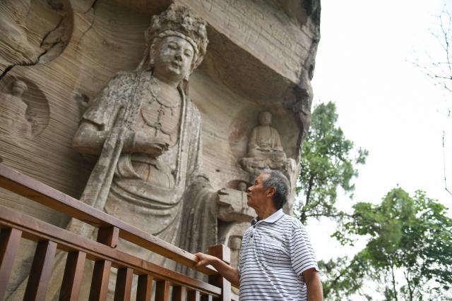 (250705) -- ZIYANG, July 5, 2025 (Xinhua) -- Zeng Xiangyu inspects stone carvings at Mingshan Temple in Shiyang Town of Ziyang City, southwest China's Sichuan Province, June 14, 2025. On top of Hutou Mountain in Shiyang Town of Ziyang City, a 76-year-old man named Zeng Xiangyu is a familiar sight to locals. Accompanied by his dog, he patrols the circular path around Mingshan Temple, meticulously inspecting each stone carving.
   Dating back to the Tang Dynasty (618-907), Mingshan Temple houses over 60 statues inside 13 caves. Most of these magnificent works of artistry were chiseled during the Song Dynasty (960-1127).
   In the 1980s, Zeng first came to the mountain with his uncle for temple renovation work. Since then, he has devoted his life to safeguarding these relics. When Mingshan Temple was listed as a national key cultural relics protection site in 2006, Zeng formally became its on-site cultural heritage administrator.
   Today, as visitors flock to Mingshan Temple, Zeng occasionally steps into a part-time role as a guide, narrating centuries-old tales. He has expressed that he wishes to protect these sculptural treasures passed down from ancestors to future generations. (Xinhua/Xu Bingjie)