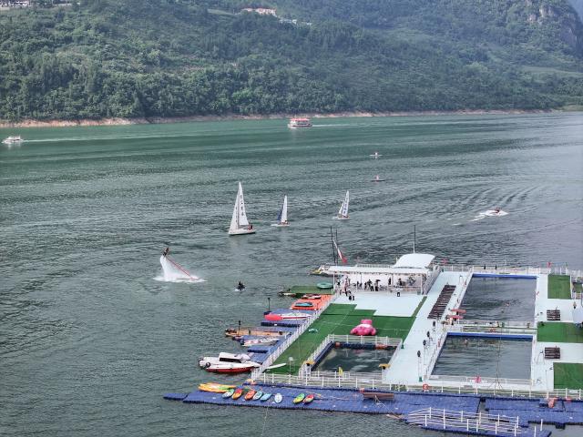 (250708) -- ENSHI, July 8, 2025 (Xinhua) -- An aerial drone photo taken on July 7, 2025 shows tourists experiencing water sports activities at an aquatic sports center in Jianshi County, Enshi Tujia and Miao Autonomous Prefecture, central China's Hubei Province. Enshi is a well-known summer travel destination in central China. Tapping diverse ecological resources, such as unique karst landforms, pleasant alpine climate, and dense primeval forests, the local authorities have actively developed summer tourism, and meticulously created diversified tourism products, like exploring canyon and cave, rafting on Qingjiang River and experiencing the culture of Tujia ethnic group. (Photo by Zhao Jun/Xinhua)