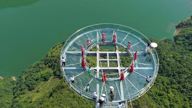 (250708) -- ENSHI, July 8, 2025 (Xinhua) -- An aerial drone photo taken on July 7, 2025 shows tourists visiting a glass skywalk in Shuibuya Township of Badong County, Enshi Tujia and Miao Autonomous Prefecture, central China's Hubei Province. Enshi is a well-known summer travel destination in central China. Tapping diverse ecological resources, such as unique karst landforms, pleasant alpine climate, and dense primeval forests, the local authorities have actively developed summer tourism, and meticulously created diversified tourism products, like exploring canyon and cave, rafting on Qingjiang River and experiencing the culture of Tujia ethnic group. (Photo by Yang Shunpi/Xinhua)