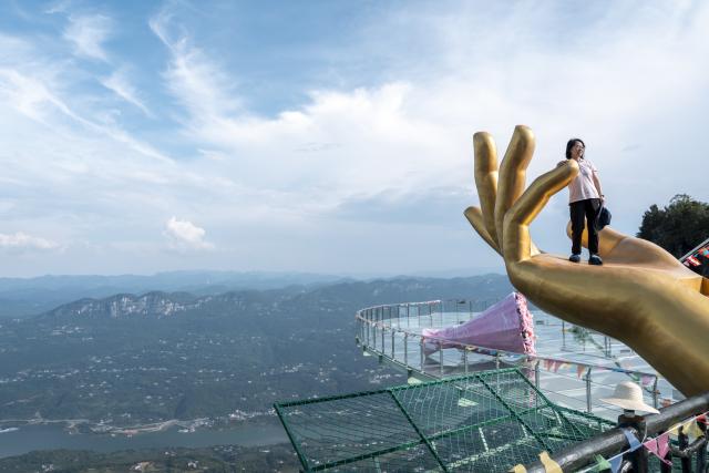 (250708) -- ENSHI, July 8, 2025 (Xinhua) -- A tourist visits a scenic area in Jianshi County, Enshi Tujia and Miao Autonomous Prefecture, central China's Hubei Province, July 7, 2025. Enshi is a well-known summer travel destination in central China. Tapping diverse ecological resources, such as unique karst landforms, pleasant alpine climate, and dense primeval forests, the local authorities have actively developed summer tourism and meticulously created diversified tourism products, like exploring canyon and cave, rafting on Qingjiang River and experiencing the culture of Tujia ethnic group. (Xinhua/Wu Zhizun)