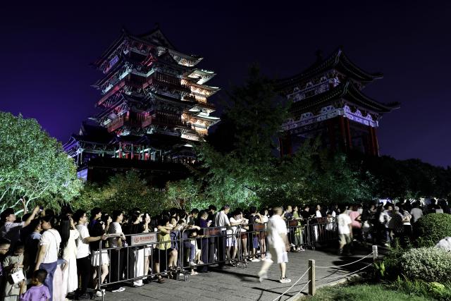 (250708) -- NANCHANG, July 8, 2025 (Xinhua) -- Tourists queue at the Tengwang Pavilion scenic area at night in Nanchang City, east China's Jiangxi Province, on July 7, 2025. The Tengwang Pavilion, the 29th iteration in its 1,400-year history, features intricately carved beams and vibrantly painted rafters. It stands majestically along the banks of the Ganjiang River, which winds through eastern China's Jiangxi Province. About 90 percent of the scenic area has been open to the public for free as of Jan. 1 this year when a northward expansion project was fully completed. (Xinhua/Liu Jinhai)