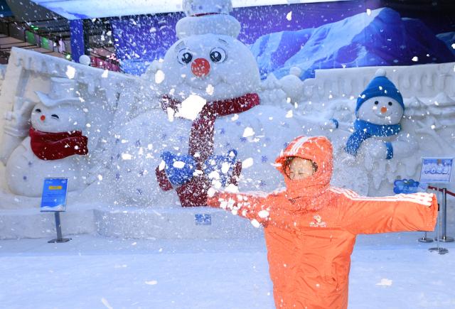 (250709) -- HARBIN, July 9, 2025 (Xinhua) -- A tourist plays with artificial snow at the ice and snow art gallery of the Sun Island scenic spot in Harbin, northeast China's Heilongjiang Province, on July 9, 2025. The newly upgraded ice and snow art gallery of the Sun Island scenic spot opened to public recently, enabling visitors to enjoy ice and snow in summer. (Photo by Liu Yang/Xinhua)