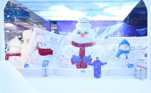 (250709) -- HARBIN, July 9, 2025 (Xinhua) -- A tourist plays with artificial snow at the ice and snow art gallery of the Sun Island scenic spot in Harbin, northeast China's Heilongjiang Province, on July 9, 2025. The newly upgraded ice and snow art gallery of the Sun Island scenic spot opened to public recently, enabling visitors to enjoy ice and snow in summer. (Photo by Liu Yang/Xinhua)