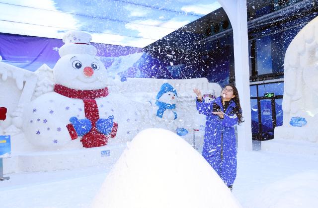 (250709) -- HARBIN, July 9, 2025 (Xinhua) -- A tourist plays with artificial snow at the ice and snow art gallery of the Sun Island scenic spot in Harbin, northeast China's Heilongjiang Province, on July 9, 2025. The newly upgraded ice and snow art gallery of the Sun Island scenic spot opened to public recently, enabling visitors to enjoy ice and snow in summer. (Photo by Liu Yang/Xinhua)