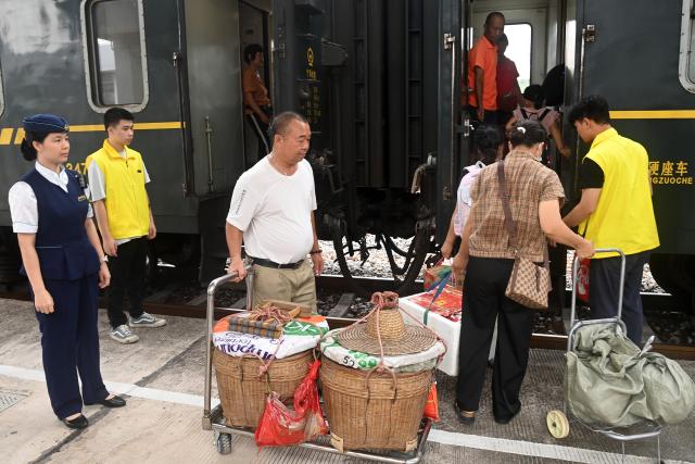 (250711) -- NANNING, July 11, 2025 (Xinhua) -- Fruit farmers and passengers line up to board the train at Hechun Station of Litang-Zhanjiang Railway, south China's Guangdong Province, July 10, 2025. The green-painted trains running on the Litang-Zhanjiang Railway offer a very cost-effective ride to fruit farmers. The relatively slow trains stop at more stations compared with the speedy bullet trains. To provide convenience for farmers to sell their fruits, the railway department has set up special waiting areas at the stations, and the railway staff often offer a helping hand to them who are carrying heavy baskets. (Xinhua/Lu Boan)