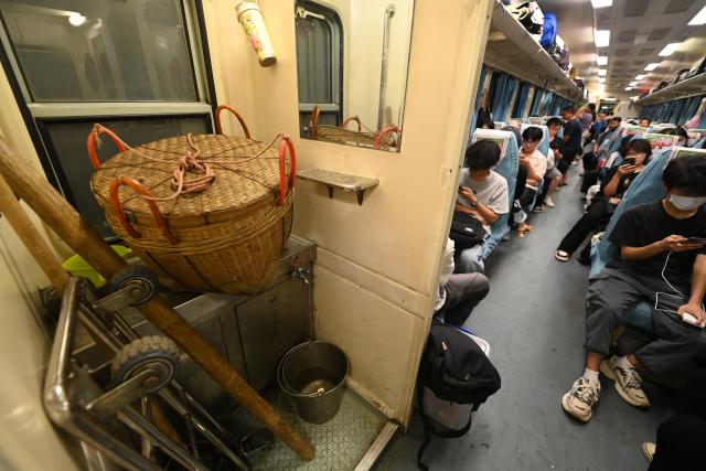 (250711) -- NANNING, July 11, 2025 (Xinhua) -- Baskets carrying poles and a cart are seen at a train bound for Zhanjiang City of south China's Guangdong Province from Nanning City of Guangxi Zhuang Autonomous Region, south China, July 9, 2025. The green-painted trains running on the Litang-Zhanjiang Railway offer a very cost-effective ride to fruit farmers. The relatively slow trains stop at more stations compared with the speedy bullet trains. To provide convenience for farmers to sell their fruits, the railway department has set up special waiting areas at the stations, and the railway staff often offer a helping hand to them who are carrying heavy baskets. (Xinhua/Lu Boan)