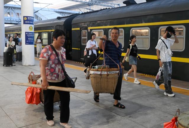 (250711) -- NANNING, July 11, 2025 (Xinhua) -- Fruit farmers who have sold their fruits walk on the platform to take the train home at Yulin Station of Litang-Zhanjiang Railway, south China's Guangxi Zhuang Autonomous Region, July 9, 2025. The green-painted trains running on the Litang-Zhanjiang Railway offer a very cost-effective ride to fruit farmers. The relatively slow trains stop at more stations compared with the speedy bullet trains. To provide convenience for farmers to sell their fruits, the railway department has set up special waiting areas at the stations, and the railway staff often offer a helping hand to them who are carrying heavy baskets. (Xinhua/Lu Boan)