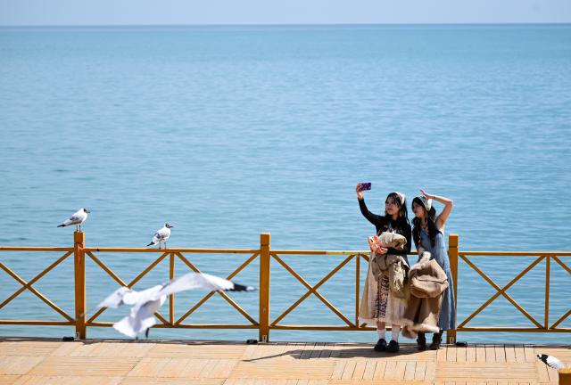 (250712) -- XINING, July 12, 2025 (Xinhua) -- Tourists take a selfie at the Dongge'er fish-watching platform of Qinghai Lake, northwest China's Qinghai Province, April 11, 2024. (Xinhua/Zhang Long)