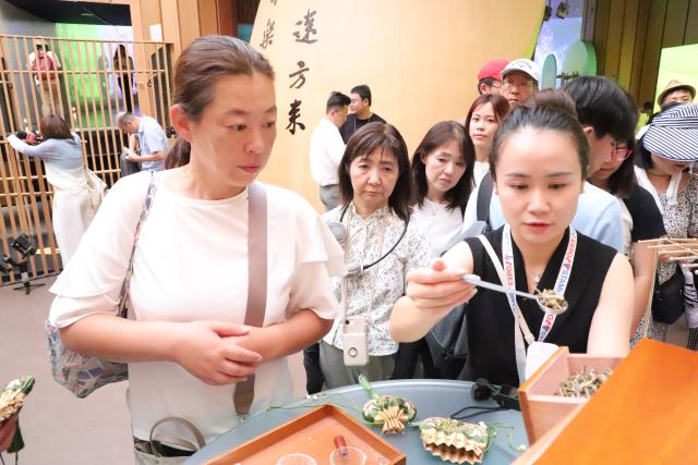 (250712) -- OSAKA, July 12, 2025 (Xinhua) -- A staff member demonstrates the making of traditional Chinese medicine sachets at the "Zhejiang Week" of China Pavilion at the Expo 2025 Osaka, in Osaka, Japan, on July 12, 2025. The "Zhejiang Week" of China Pavilion at the Expo 2025 Osaka kicked off on Saturday. (Xinhua/Li Guangzheng)