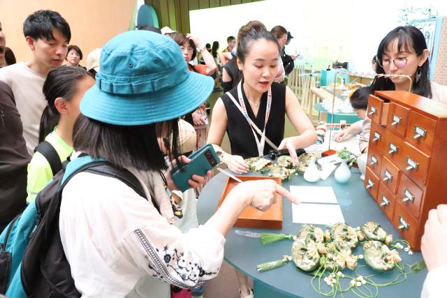 (250712) -- OSAKA, July 12, 2025 (Xinhua) -- People try their hands at making traditional Chinese medicine sachets at the "Zhejiang Week" of China Pavilion at the Expo 2025 Osaka, in Osaka, Japan, on July 12, 2025. The "Zhejiang Week" of China Pavilion at the Expo 2025 Osaka kicked off on Saturday. (Xinhua/Li Ziyue)