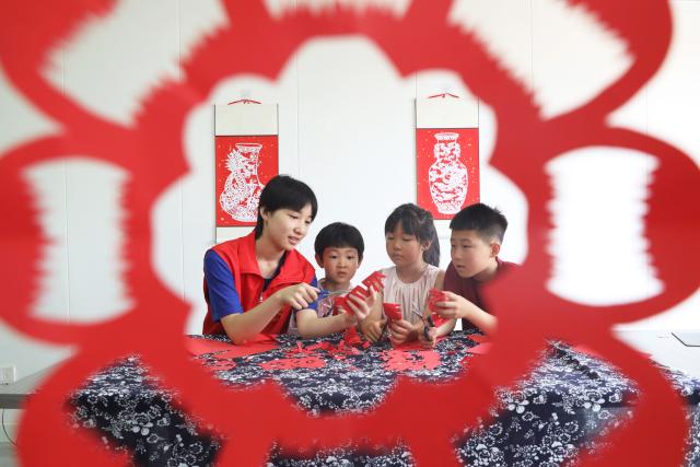(250712) -- BEIJING, July 12, 2025 (Xinhua) -- Children learn to make paper-cutting works under the guidance of a volunteer in Fengrun District of Tangshan City, north China's Hebei Province, July 11, 2025. Children across the country are enriching their summer vacations through colorful activities. (Photo by Zhu Dayong/Xinhua)