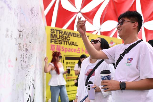 (250712) -- URUMQI, July 12, 2025 (Xinhua) -- People sign on the signature wall during the Strawberry Music Festival in Urumqi, northwest China's Xinjiang Uygur Autonomous Region, July 12, 2025. The 2025 Strawberry Music Festival kicked off in Urumqi on Saturday. (Photo by Xu Rui/Xinhua)