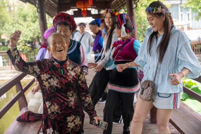 (250713) -- BEIJING, July 13, 2025 (Xinhua) -- Tourists dance with local people in Dali Bai Autonomous Prefecture, southwest China's Yunnan Province, July 12, 2025. Tourist destinations in Yunnan entered their peak tourism season as summer vacation began. (Photo by Luo Xincai/Xinhua)