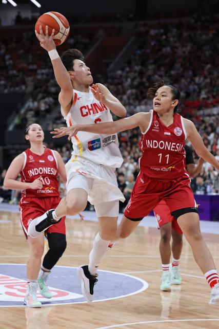 (250713) -- SHENZHEN, July 13, 2025 (Xinhua) -- Yang Shuyu (C) of China shoots under the defense of Faizzatus Shoimah (R) of Indonesia during the Group A match between China and Indonesia of FIBA Women's Asia Cup Division A in Shenzhen, south China's Guangdong Province, July 13, 2025. (Xinhua/Liang Xu)