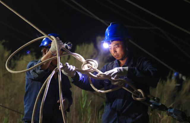 (250713) -- MINFENG, July 13, 2025 (Xinhua) -- Chen Lin (R) works with his colleague at a construction site in Minfeng County, of Hotan Prefecture, northwest China's Xinjiang Uygur Autonomous Region, early July 10, 2025. China has finished construction of a 4,197-km extra-high voltage power transmission loop around the Tarim Basin, home to the country's largest desert, marking a major infrastructure milestone in southern Xinjiang Uygur Autonomous Region.
   The final section of the 750-kilovolt (kV) loop, now the country's largest of its kind, was connected on Sunday, capping a 15-year project involving nine substations and nearly 10,000 steel towers, according to a subsidiary of State Grid Xinjiang Electric Power Co., Ltd., which constructed the project.
   The transmission line passes through extreme terrain, from the shifting sands of the desert to the high altitudes of the Kunlun Mountains.
   Chen Lin arrived in March this year at the southern edge of the Taklimakan Desert, where he, side by side with over 40 colleagues, accomplished part of the transmission line construction work despite sandy gusts and scorching temperature. (Photo by Zhang Limin/Xinhua)