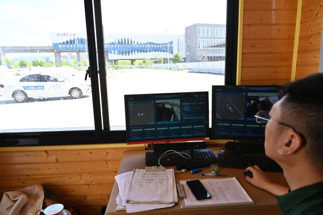(250715) -- DONGYANG, July 15, 2025 (Xinhua) -- A coach monitors real-time status of AI-driven training vehicles at the Xinlong driving school in Dongyang, east China's Zhejiang Province, July 2, 2025. The driving school has introduced an AI-assisted teaching system, which includes AI-driven training vehicles, indoor driving simulators, and AI-powered data management system. Equipped with 16 vehicle-borne radars and visual assistance system, each AI-driven training vehicle serves as an intelligent alternative to a driving coach, providing comprehensive and safe guidance for trainees. (Photo by Bao Kangxuan/Xinhua)
