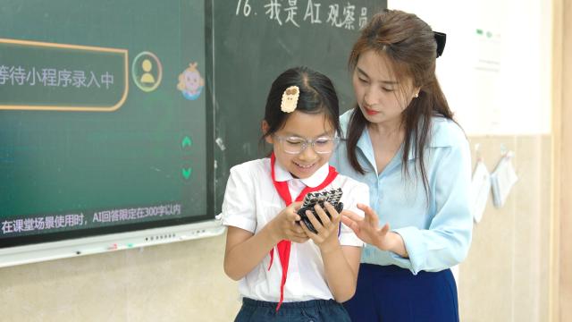(250715) -- CHONGQING, July 15, 2025 (Xinhua) -- This photo taken in June 2024 shows a teacher instructing a student to use AI on mobile phone in Lijia Experimental Primary School in southwest China's Chongqing Municipality. TO GO WITH "Across China: AI revolution transforms learning for students in China's Chongqing" (Xinhua)
