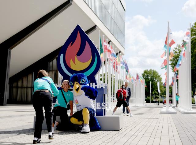 (250716) -- ESSEN, July 16, 2025 (Xinhua) -- Volunteers pose with the mascot "Wanda" at the Flag Plaza for the Rhine-Ruhr 2025 FISU World University Games in Essen,Germany, July 15, 2025. (Xinhua/Zhang Chen)