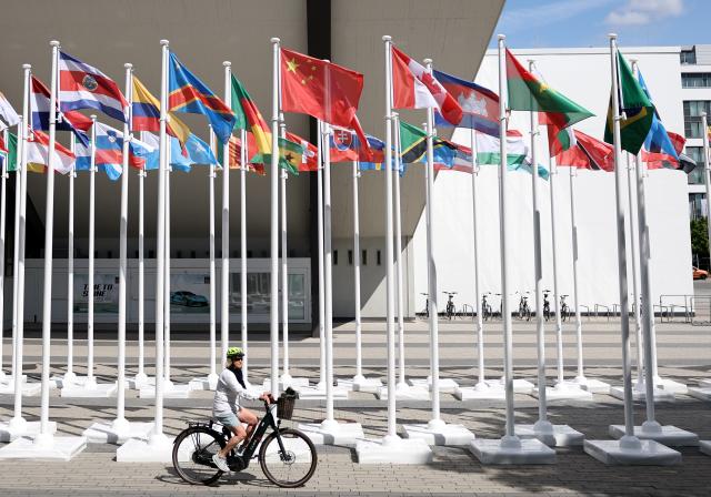 (250716) -- ESSEN, July 16, 2025 (Xinhua) -- A woman rides past the Flag Plaza for the Rhine-Ruhr 2025 FISU World University Games in Essen, Germany, July 15, 2025. (Xinhua/Zhang Chen)