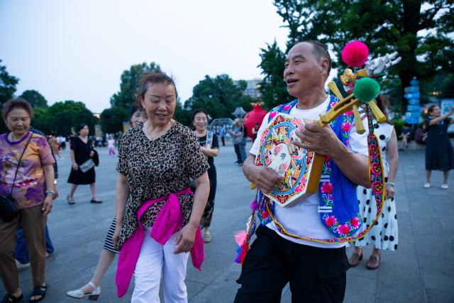 (250716) -- KUNMING, July 16, 2025 (Xinhua) -- Tourists experience folk activities with locals at a square in Qujing City, southwest China's Yunnan Province, July 15, 2025. Known for its stunning nature beauty, Yunnan Province has cultivated a summer tourism industry, offering tourists diverse experiences amid forests, snow-capped mountains, wetlands, and flower fields. (Photo by Yang Junpeng/Xinhua)