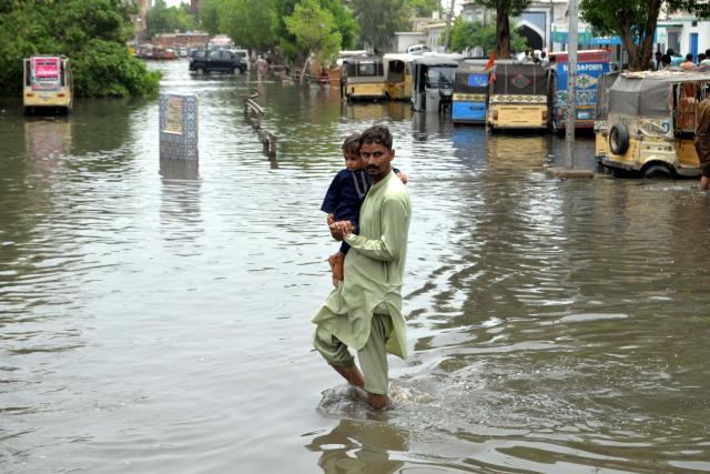 (250716) -- HYDERABAD, July 16, 2025 (Xinhua) -- A man carries his child as he wades through flood water after heavy monsoon rains in southern Pakistan's Hyderabad on July 15, 2025. Torrential monsoon rains and associated incidents have left at least 124 people dead and 264 others injured across Pakistan over the past three weeks, the National Disaster Management Authority (NDMA) said Wednesday. (Str/Xinhua)