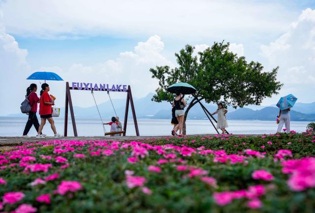 (250717) -- YUXI, July 17, 2025 (Xinhua) -- Tourists enjoy the view by Fuxian Lake in Yuxi City, southwest China's Yunnan Province on July 16, 2025. The beautiful scenery of Fuxian Lake in summer has attracted tourists nationwide. (Xinhua/Chen Xinbo)