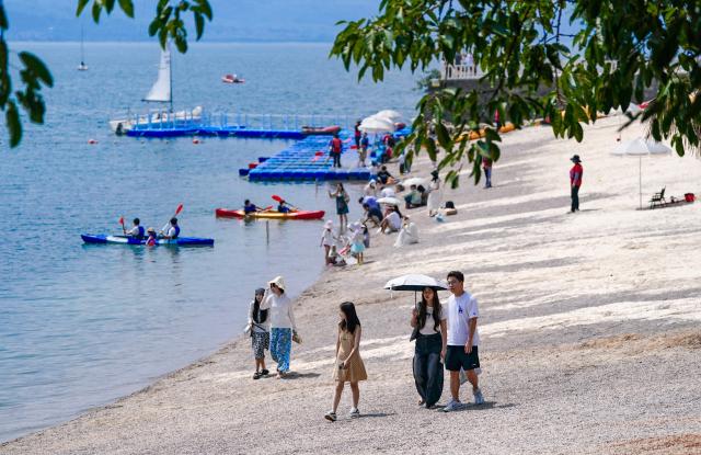 (250717) -- YUXI, July 17, 2025 (Xinhua) -- Tourists enjoy the view by Fuxian Lake in Yuxi City, southwest China's Yunnan Province on July 16, 2025. The beautiful scenery of Fuxian Lake in summer has attracted tourists nationwide. (Xinhua/Chen Xinbo)