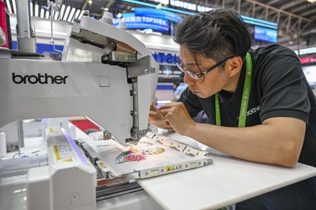 (250717) -- BEIJING, July 17, 2025 (Xinhua) -- A staff member adjusts a commercial embroidery machine at the booth of Brother (China) in the Advanced Manufacturing Chain area of the third China International Supply Chain Expo (CISCE) in Beijing, capital of China, July 16, 2025. Held from July 16 to 20, the 2025 CISCE kicked off in Beijing on Wednesday. A key innovation for this edition is the "Debut Zone," dedicated to the global premieres of new products, technologies, and ecosystems, showcasing breakthrough innovations that drive industrial collaboration. (Xinhua/Chen Shuo)