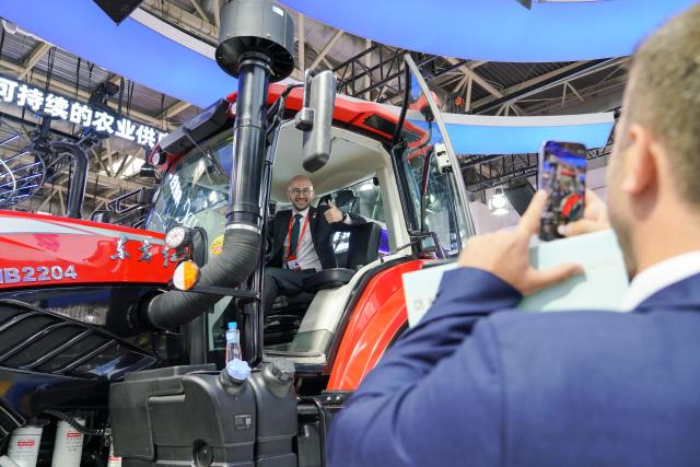 (250717) -- BEIJING, July 17, 2025 (Xinhua) -- A visitor poses for photos with a tractor at the booth of China National Machinery Industry Corporation (Sinomach) in the Green Agriculture Chain area of the third China International Supply Chain Expo (CISCE) in Beijing, capital of China, July 16, 2025. Held from July 16 to 20, the 2025 CISCE kicked off in Beijing on Wednesday. A key innovation for this edition is the "Debut Zone," dedicated to the global premieres of new products, technologies, and ecosystems, showcasing breakthrough innovations that drive industrial collaboration. (Xinhua/Wang Jingyi)