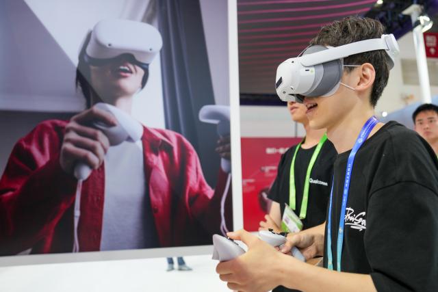 (250717) -- BEIJING, July 17, 2025 (Xinhua) -- A visitor tries a product at the booth of Qualcomm in the Digital Technology Chain area of the third China International Supply Chain Expo (CISCE) in Beijing, capital of China, July 17, 2025. Held from July 16 to 20, the 2025 CISCE kicked off in Beijing on Wednesday. A key innovation for this edition is the "Debut Zone," dedicated to the global premieres of new products, technologies, and ecosystems, showcasing breakthrough innovations that drive industrial collaboration. (Xinhua/Ju Huanzong)