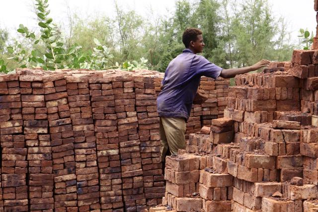(250718) -- OMDURMAN, July 18, 2025 (Xinhua) -- A worker stacks fired bricks in Omdurman, north of the Sudanese capital Khartoum, Sudan, July 17, 2025. Following the Sudanese army's recapture of Khartoum from the paramilitary Rapid Support Forces, displaced residents began returning home. Facing ruined homes and scarce resources, they started to rebuild houses using whatever materials available. Along the Nile in Khartoum and Omdurman, workers shape seasonal silt into bricks, then dry and fire them as generations before. (Photo by Mohamed Khidir/Xinhua)