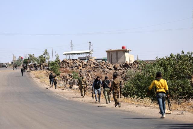 (250718) -- SWEIDA, July 18, 2025 (Xinhua) -- Tribal fighters walk along a road near a frontline in the town of Wolgha, western countryside of Sweida, southern Syria, on July 18, 2025. The Syrian interim authorities on Friday issued a call for restraint amid escalating violence in the southern province of Sweida, pledging to deploy forces to contain the conflict. (Str/Xinhua)