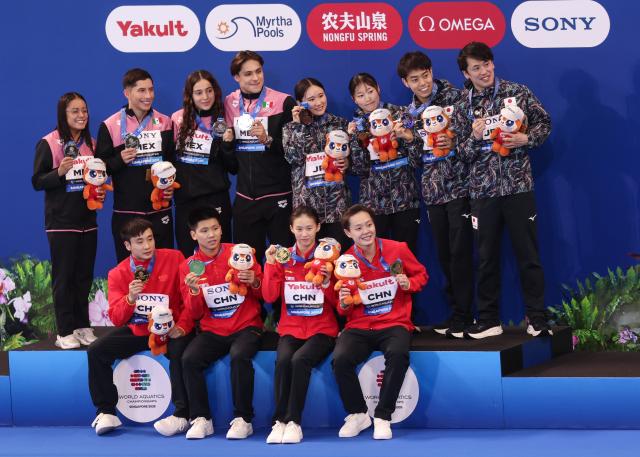 (250726) -- SINGAPORE, July 26, 2025 (Xinhua) -- Gold medalists Team China (bottom), silver medalists Team Mexico (top L) and bronze medalists Team Japan pose for photo during the awarding ceremony for the mixed 3m & 10m team of diving at the World Aquatics Championships in Singapore, July 26, 2025. (Xinhua/Luo Yuan)