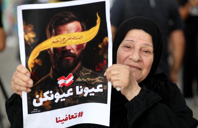 (250918) -- BEIRUT, Sept. 18, 2025 (Xinhua) -- A woman holds a sign showing support for the victims of the pager explosion on the first anniversary of the attack in Beirut, Lebanon, on Sept. 17, 2025. (Xinhua/Bilal Jawich)