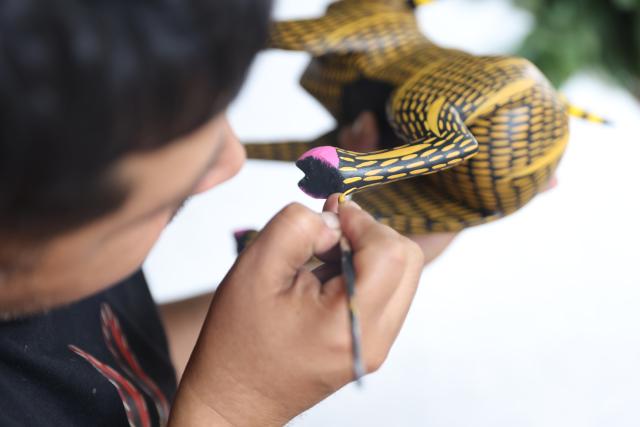 (250918) -- OAXACA, Sept. 18, 2025 (Xinhua) -- An artisan paints on a wood carving at a workshop in San Antonio Arrazola, Oaxaca State, Mexico, on Sept. 16, 2025. The village of San Antonio Arrazola on the outskirts of Oaxaca City is renowned for its colorful wood carvings. The process of making a wood carving includes chopping out shapes from the wood, carving, polishing, and applying hand-painted designs. These wood carvings often draw inspirations from animals, infused with fantasy and mythological elements. The craft is not only a signature local folk art but also a vital source of income for many local families. (Xinhua/Li Mengxin)