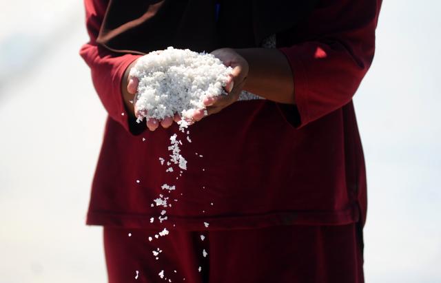(250918) -- SIDOARJO, Sept. 18, 2025 (Xinhua) -- A farmer shows freshly-harvested salt at Tambak Cemandi village in Sidoarjo, East Java, Indonesia, Sept. 18, 2025. Indonesia aims to achieve salt self-sufficiency by 2027, with the government rolling out a series of programs to boost national salt production capacity, the Ministry of Marine and Fisheries Affairs said at a parliamentary hearing on Tuesday. (Photo by Sahlan Kurniawan/Xinhua)