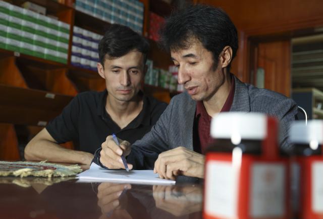(250919) -- URUMQI, Sept. 19, 2025 (Xinhua) -- Metkasim Manglik (R) teaches his nephew to prepare herbal tea at his herbal tea shop in Qira County, northwest China's Xinjiang Uygur Autonomous Region, Sept. 5, 2025.
  Hotan herbal tea has a long history and drinking tea has become an essential part of people's daily life here. It is made from more than 30 ingredients such as cloves, goji berries, ginger, dried tangerine peel, and roses, which are smashed before brewing. In 2021, the technique of making Hotan herbal tea was listed as a national-level intangible cultural heritage.
  Metkasim Manglik, one of the inheritors of Hotan herbal tea making, comes from a family that has been producing the tea since his grandfather. Starting at the age of 15, Metkasim began assisting his father in his family's business. Later, he studied at a local medical school and graduated in 2008. In 2019, Metkasim established his own company and created a product brand, categorizing and packaging Hotan herbal tea based on its health benefits.
  As an inheritor of the Hotan herbal tea making technique, Metkasim has had opportunities to participate in exhibitions and exchange programs in other regions. In places like east China's Anhui Province and southwest China's Sichuan Province, he has introduced his hometown's tea, receiving warm responses and even attracting interest from international visitors. The diverse local products and modern tea processing he encountered have given him more inspirations. "I'm excited that our Hotan herbal tea is gaining recognition, which motivates me even more to provide more tailored products for the customers," said Metkasim. (Xinhua/Wang Fei)