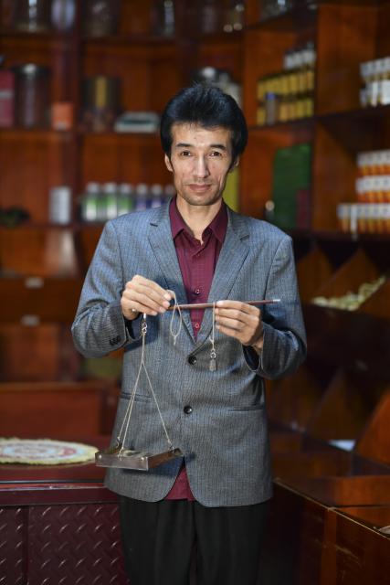 (250919) -- URUMQI, Sept. 19, 2025 (Xinhua) -- Metkasim Manglik poses for a photo at his herbal tea shop in Qira County, northwest China's Xinjiang Uygur Autonomous Region, Sept. 6, 2025.
  Hotan herbal tea has a long history and drinking tea has become an essential part of people's daily life here. It is made from more than 30 ingredients such as cloves, goji berries, ginger, dried tangerine peel, and roses, which are smashed before brewing. In 2021, the technique of making Hotan herbal tea was listed as a national-level intangible cultural heritage.
  Metkasim Manglik, one of the inheritors of Hotan herbal tea making, comes from a family that has been producing the tea since his grandfather. Starting at the age of 15, Metkasim began assisting his father in his family's business. Later, he studied at a local medical school and graduated in 2008. In 2019, Metkasim established his own company and created a product brand, categorizing and packaging Hotan herbal tea based on its health benefits.
  As an inheritor of the Hotan herbal tea making technique, Metkasim has had opportunities to participate in exhibitions and exchange programs in other regions. In places like east China's Anhui Province and southwest China's Sichuan Province, he has introduced his hometown's tea, receiving warm responses and even attracting interest from international visitors. The diverse local products and modern tea processing he encountered have given him more inspirations. "I'm excited that our Hotan herbal tea is gaining recognition, which motivates me even more to provide more tailored products for the customers," said Metkasim. (Xinhua/Wang Fei)