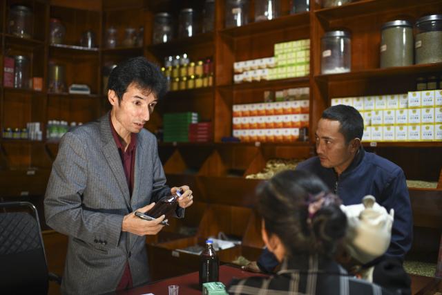 (250919) -- URUMQI, Sept. 19, 2025 (Xinhua) -- Metkasim Manglik (L) serves customers at his herbal tea shop in Qira County, northwest China's Xinjiang Uygur Autonomous Region, Sept. 5, 2025.
  Hotan herbal tea has a long history and drinking tea has become an essential part of people's daily life here. It is made from more than 30 ingredients such as cloves, goji berries, ginger, dried tangerine peel, and roses, which are smashed before brewing. In 2021, the technique of making Hotan herbal tea was listed as a national-level intangible cultural heritage.
  Metkasim Manglik, one of the inheritors of Hotan herbal tea making, comes from a family that has been producing the tea since his grandfather. Starting at the age of 15, Metkasim began assisting his father in his family's business. Later, he studied at a local medical school and graduated in 2008. In 2019, Metkasim established his own company and created a product brand, categorizing and packaging Hotan herbal tea based on its health benefits.
  As an inheritor of the Hotan herbal tea making technique, Metkasim has had opportunities to participate in exhibitions and exchange programs in other regions. In places like east China's Anhui Province and southwest China's Sichuan Province, he has introduced his hometown's tea, receiving warm responses and even attracting interest from international visitors. The diverse local products and modern tea processing he encountered have given him more inspirations. "I'm excited that our Hotan herbal tea is gaining recognition, which motivates me even more to provide more tailored products for the customers," said Metkasim. (Xinhua/Hu Huhu)