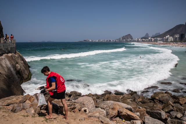 (250921) -- RIO DE JANEIRO, Sept. 21, 2025 (Xinhua) -- A volunteer picks up trash at Copacabana Beach, Rio de Janeiro, Brazil, Sept. 20, 2025. World Cleanup Day is an annual global event that is marked every third Saturday in September with the aim of combating the global solid waste problem. (Xinhua/Wang Tiancong)