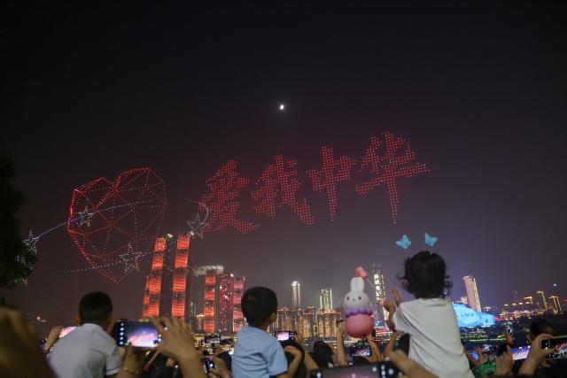 (251002) -- CHONGQING, Oct. 2, 2025 (Xinhua) -- People take photos of a drone light show staged in celebration of China's National Day in Nan'an District of southwest China's Chongqing Municipality, Oct. 1, 2025. During the show, 5,000 drones performed in the sky at night, bringing a visual feast to spectators. (Xinhua/Huang Wei)