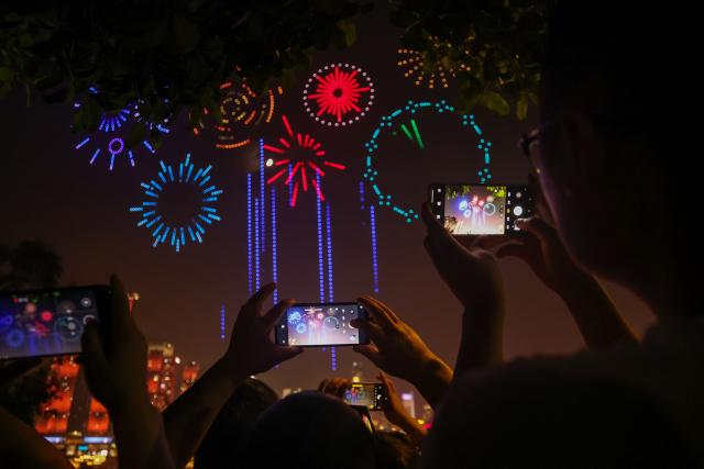 (251002) -- CHONGQING, Oct. 2, 2025 (Xinhua) -- People take photos of a drone light show staged in celebration of China's National Day in Nan'an District of southwest China's Chongqing Municipality, Oct. 1, 2025. During the show, 5,000 drones performed in the sky at night, bringing a visual feast to spectators. (Xinhua/Huang Wei)