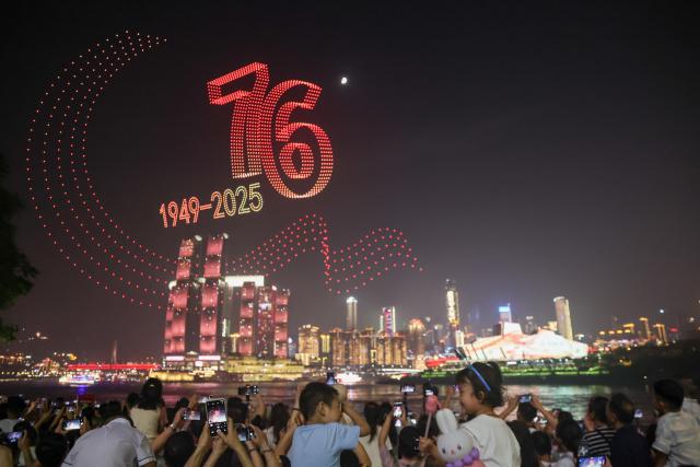 (251002) -- CHONGQING, Oct. 2, 2025 (Xinhua) -- People watch a drone light show staged in celebration of China's National Day in Nan'an District of southwest China's Chongqing Municipality, Oct. 1, 2025. During the show, 5,000 drones performed in the sky at night, bringing a visual feast to spectators. (Xinhua/Huang Wei)
