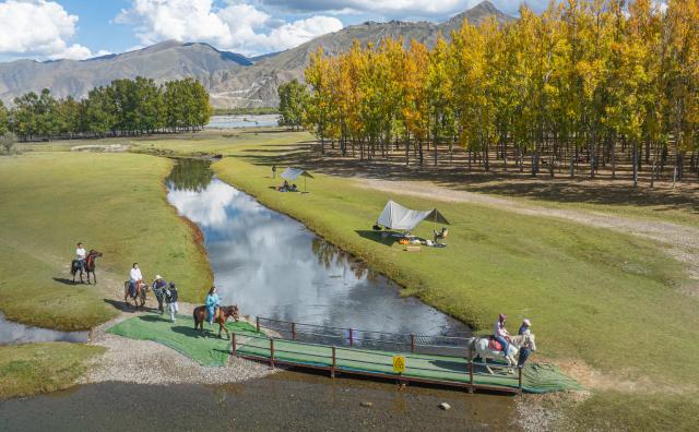 (251002) -- LHASA, Oct. 2, 2025 (Xinhua) -- An aerial drone photo taken on Sept. 27, 2025 shows tourists riding horses at a "Lingka" camping site in Lhunzhub County of Lhasa, southwest China's Xizang Autonomous Region. "Lingka" means "garden" in the Tibetan language. In Xizang, people follow a tradition of spending the "Lingka" time during which they camp out and have picnics in parks or suburbs. 
    Nowadays, this traditional folk custom has developed into a new form of cultural tourism as well as a vibrant lifestyle. (Xinhua/Tenzin Nyida)