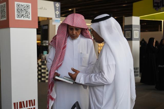 (251002) -- RIYADH, Oct. 2, 2025 (Xinhua) -- Two men talk at the Riyadh International Book Fair 2025 in Riyadh, Saudi Arabia, Oct. 2, 2025. The book fair opened here on Thursday, bringing together over 2,000 local and international publishing houses from more than 25 countries, along with a range of cultural institutions. (Xinhua/Luo Chen)